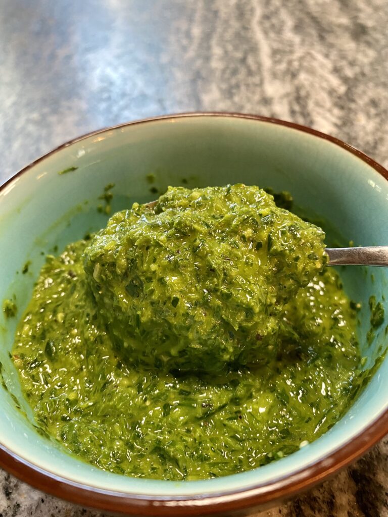 green herb sauce being spooned out of a small bowl