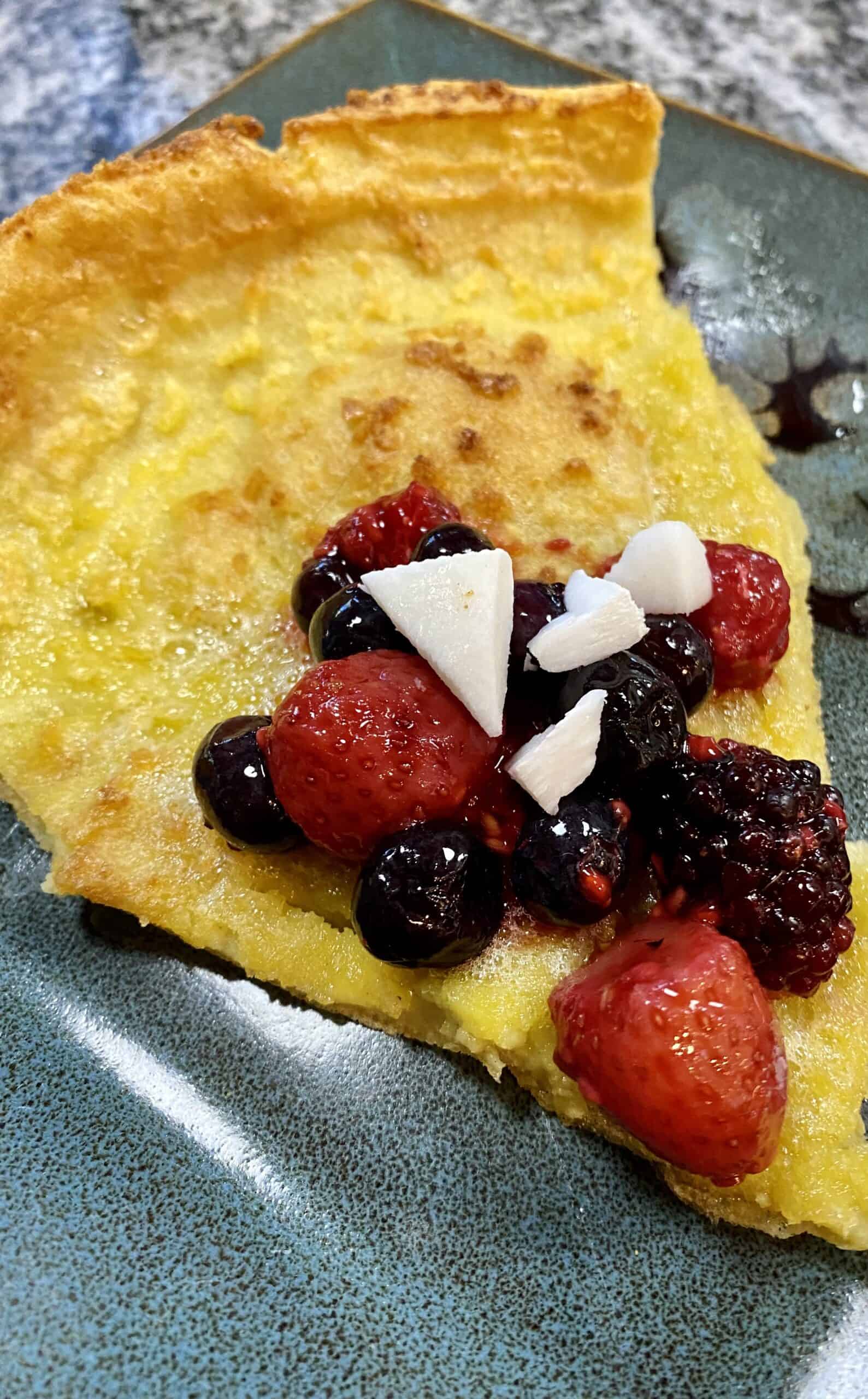 gluten and dairy free dutch baby pancake with berries and coconut on a plate